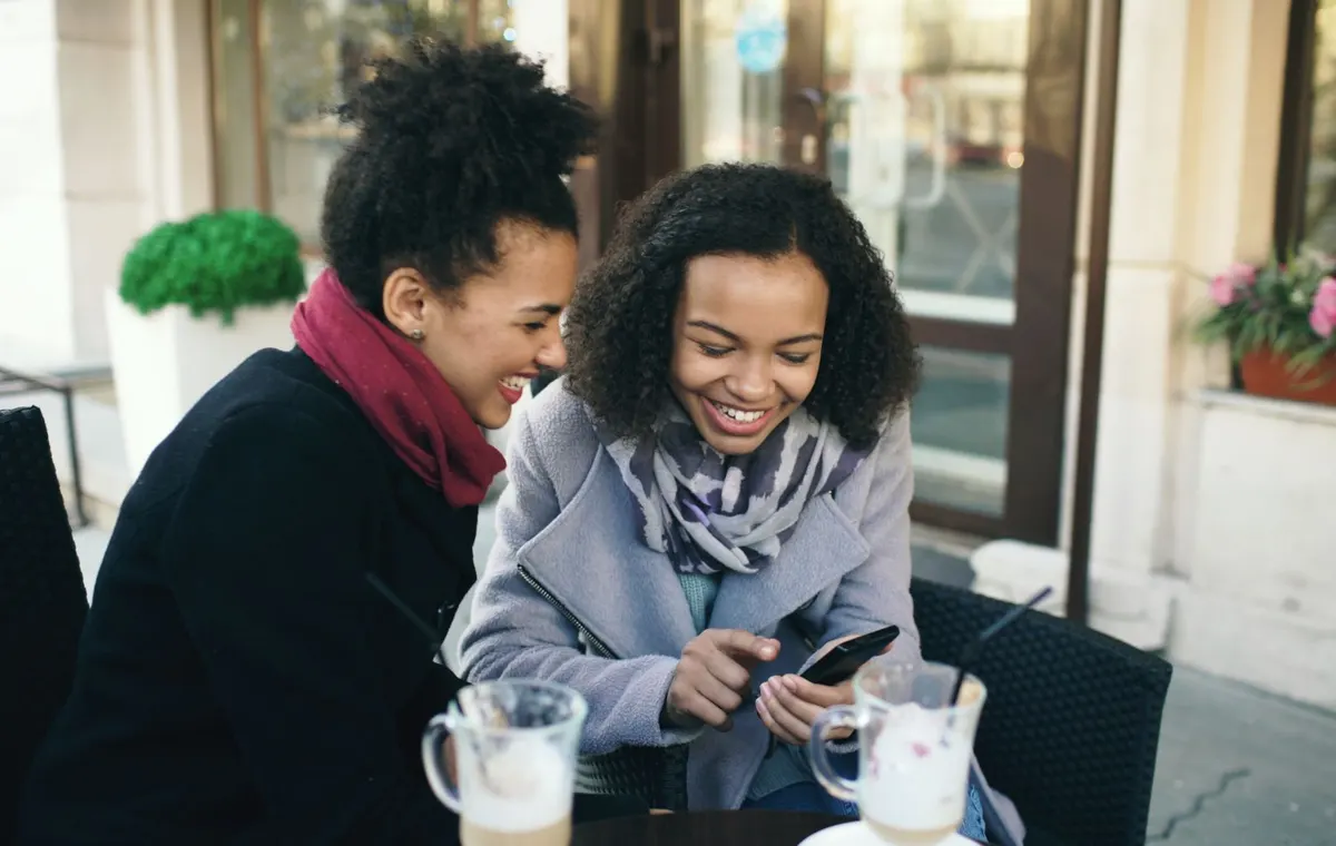 Groupe d'amies qui rient autour d'une table dans un café parisien