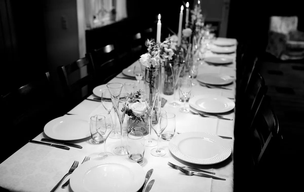 Table de dîner élégamment dressée avec bougies, fleurs et vaisselle raffinée