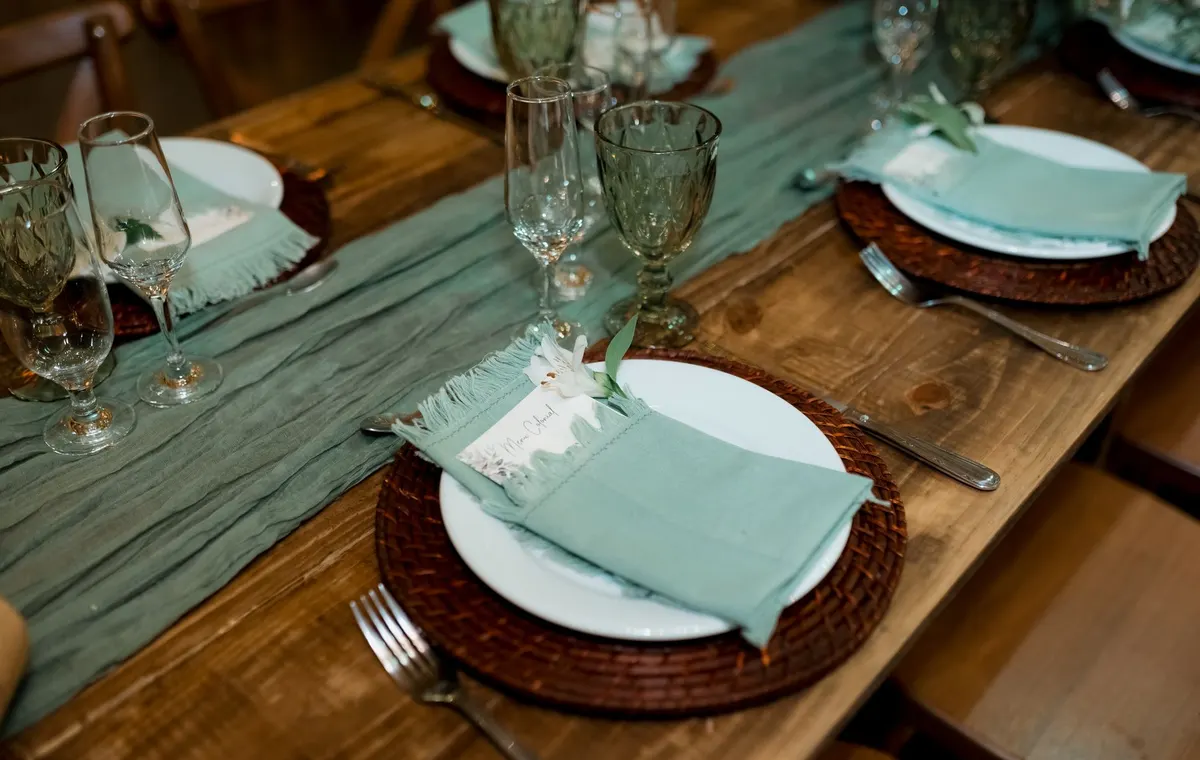 Chemin de table en lin naturel sur une table en bois avec vaisselle blanche et bougeoirs