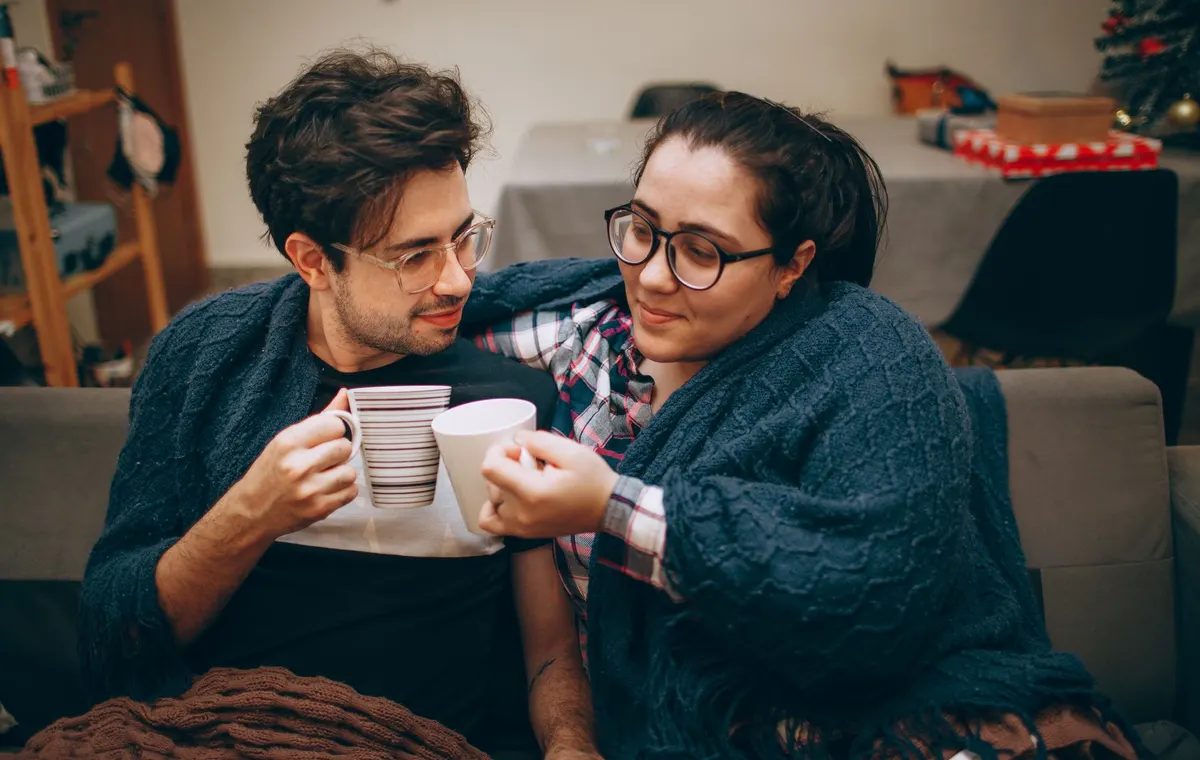 Salon cosy avec canapé moelleux, plaids et lumière tamisée créant une ambiance chaleureuse