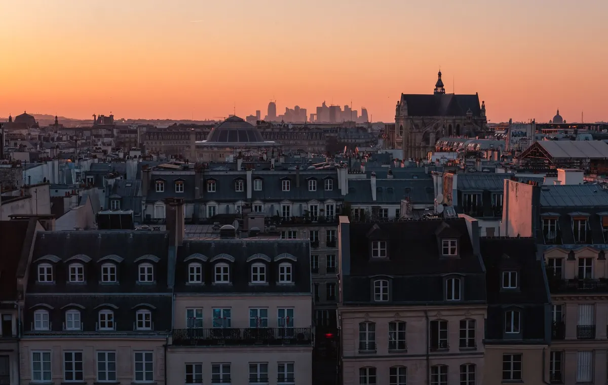 Terrasse rooftop avec vue panoramique sur les toits de Paris au coucher du soleil