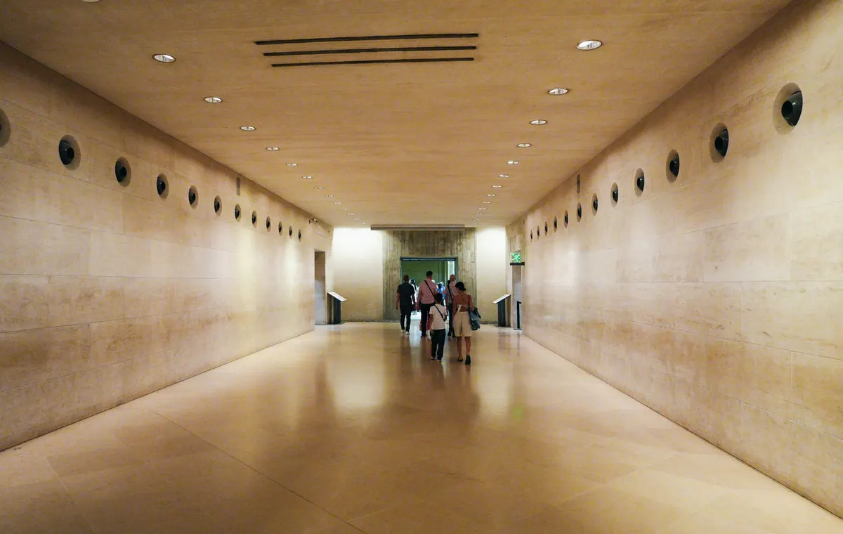 Grande salle de musée parisien avec sculptures et visiteurs