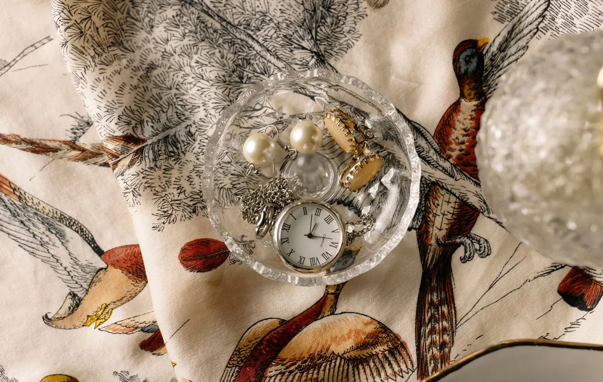 Montre ancienne et bijoux posés sur une coupelle en verre
